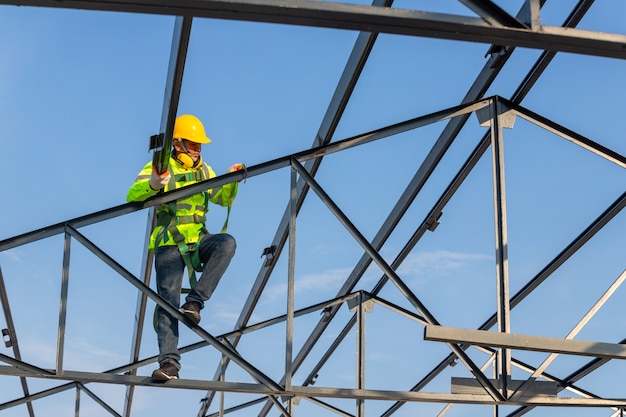 Asian roof construction worker wear safety height equipment to install the roof frame, Fall arrestor device for worker with hooks for safety body harness in the construction site.