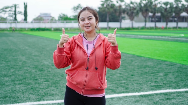 Asian runner woman wearing jacket and earphone OK gesture