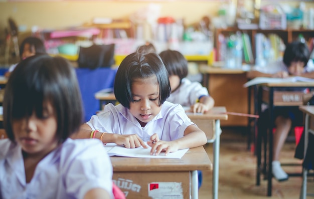 アジアの農村の学生タイの学校の机で働いています