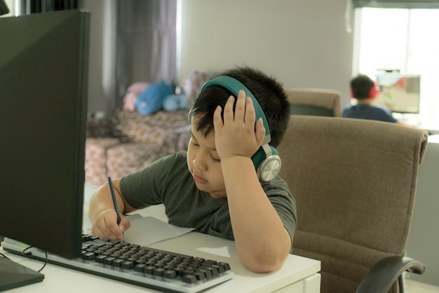 asian school boy showing the boredom during online learning at homr boring home school