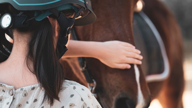 Foto ragazza del bambino della scuola asiatica con cavallo, equitazione o pratica di equitazione al ranch di cavalli.