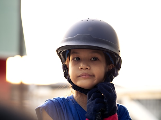 馬、乗馬、または馬の牧場での乗馬の練習をしているアジアの学校の子供の女の子。