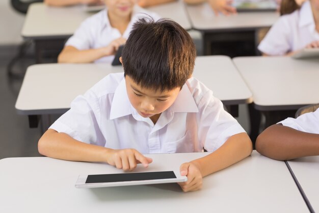 Asian schoolboy using digital tablet in classroom