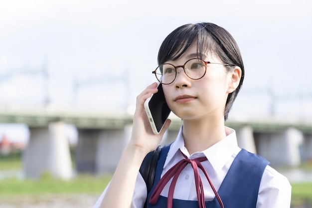 Азиатская школьница с черными короткими волосами разговаривает по смартфону