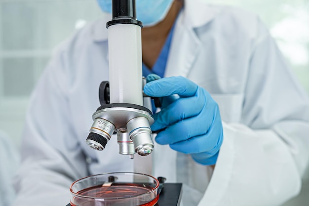 Asian scientist biochemist or microbiologist working research with a microscope in laboratory