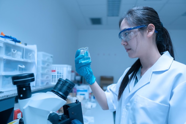 研究室で働いているアジアの科学者は、実験の結果を見つけるための研究を行っています医師は、顕微鏡検査によってコロナウイルスの新株を予防および破壊するために血液をテストしています