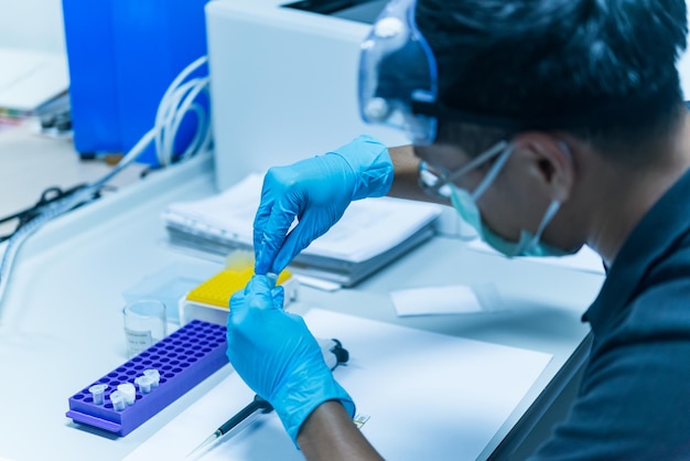 アジアの科学者はプラスチックチューブに化学物質を注入しましたラボのLabExperimentで働いているタイの科学者