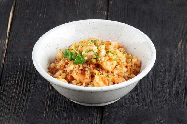 Asian seafood fried rice in a white bowl on the wooden table