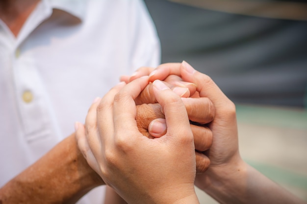 Asian senior and asian young holding hands.