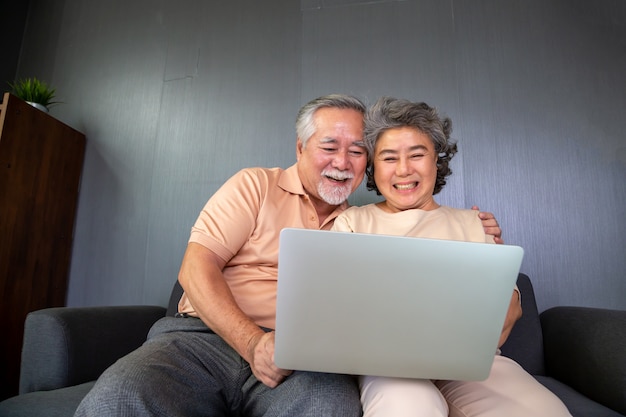 ラップトップコンピューターでビデオ通話チャットで話しているアジアの年配のカップル、高齢者のためのスマートテクノロジー、オンラインコンセプトの接続概念を維持