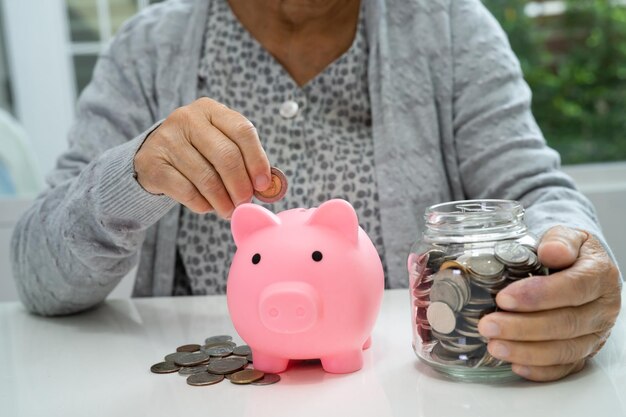 Asian senior or elderly old lady woman holding counting coin
money in piggy bank poverty saving problem in retirement poverty
saving problem in retirement