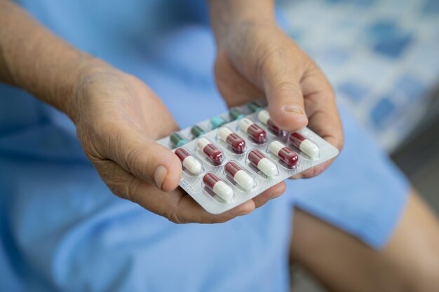 Asian senior elderly old lady woman holding Vitamin c pills drug in her hand healthy strong medical concept