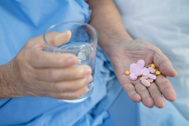 Donna anziana anziana asiatica anziana che tiene la droga delle pillole della vitamina nella sua mano concetto medico forte sano