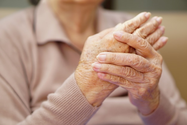 La donna anziana anziana senior o anziana asiatica sta impastando le mani dal dolore a casa. assistenza sanitaria, amore, cura, incoraggiamento ed empatia.