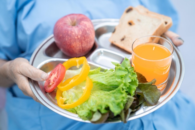 病院のベッドに座って空腹の間に希望と幸せで朝食野菜の健康食品を食べるアジアのシニアまたは高齢の老婦人女性患者。