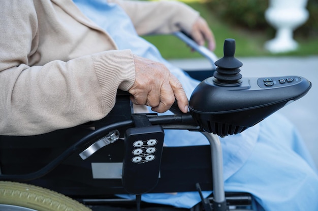 看護病棟でリモコン付き電動車椅子のアジアの高齢者または高齢者の老婦人女性患者健康強い医療概念