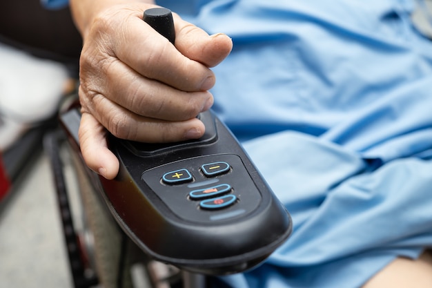 Asian senior or elderly old lady woman patient on electric wheelchair with remote control at nursing hospital ward