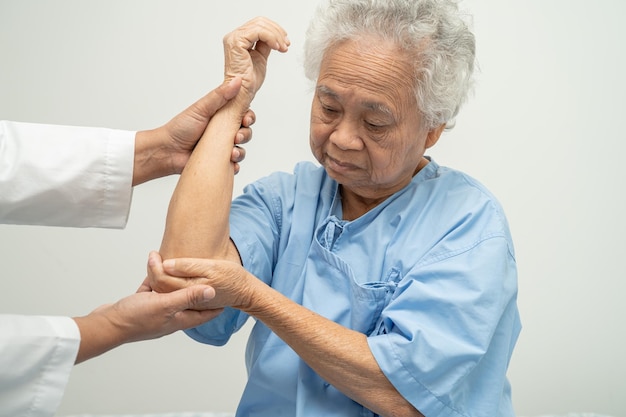 Asian senior or elderly old lady woman patient feel pain her elbow on bed in nursing hospital ward healthy strong medical concept