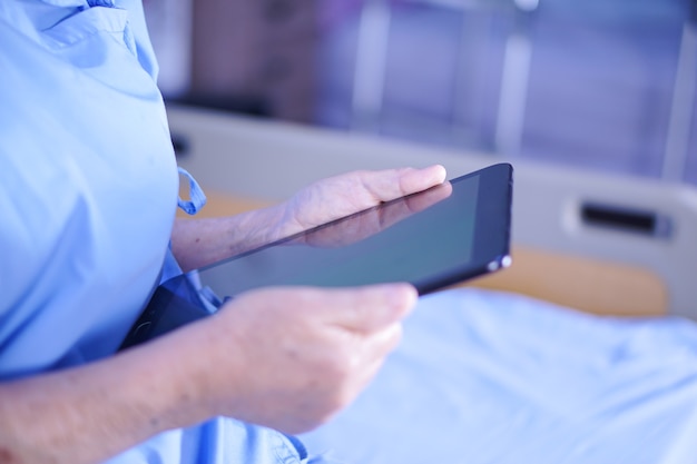 Asian senior or elderly old lady woman patient holding in her hands digital tablet.