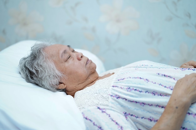Paziente della donna anziana anziana o anziana della signora anziana che si trova sul letto nell'ospedale di cura.