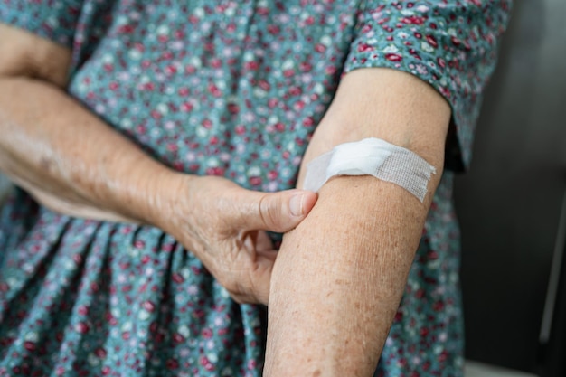 La paziente asiatica anziana o anziana mostra il cotone idrofilo smette di sanguinare dopo il test del prelievo di sangue per un controllo annuale della salute fisica per controllare la pressione sanguigna del colesterolo e il livello di zucchero