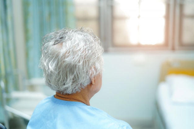 Asian senior or elderly old lady woman patient sitting on bed