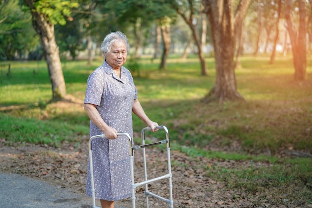 Asian senior or elderly old lady woman patient walk with walker in park : healthy strong medical concept 