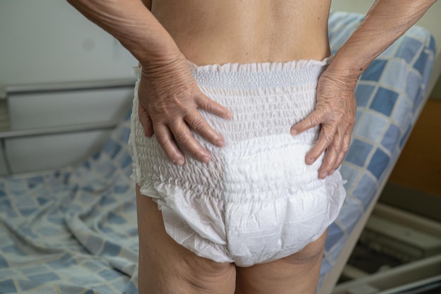 Asian senior or elderly old lady woman patient wearing incontinence diaper in nursing hospital ward healthy strong medical concept