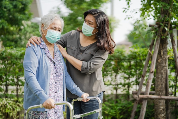 Photo asian senior or elderly old lady woman walk with walker and wearing a face mask for protect safety infection covid19 coronavirus