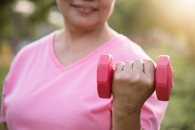 Asian Senior female lifting dumbbell.