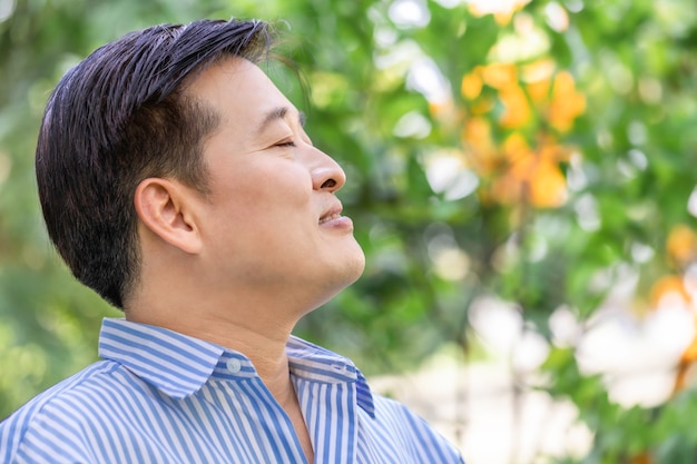 Asian senior man thinking and relaxing at the park. 