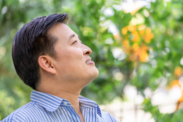 Asian senior man thinking and relaxing at the park. 