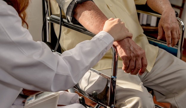 Asian Senior man was sick and sitting on wheelchair. The doctor check retirement age health at home.