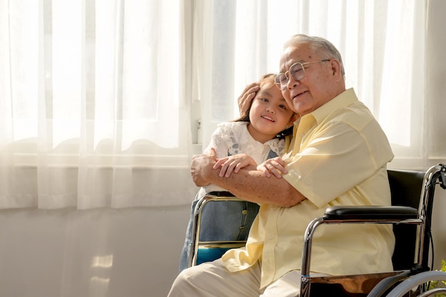 アジアの年配の男性は病気で車椅子に座っていました。定年のライフスタイルと家庭での家族との一体感。