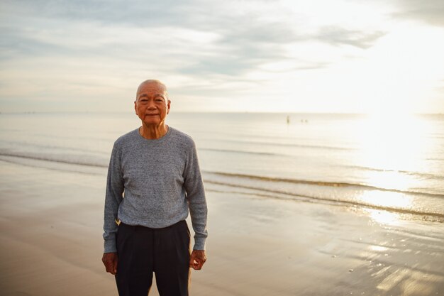 해변 일출에 아시아 수석 노인 연습 태극권과 요가 포즈