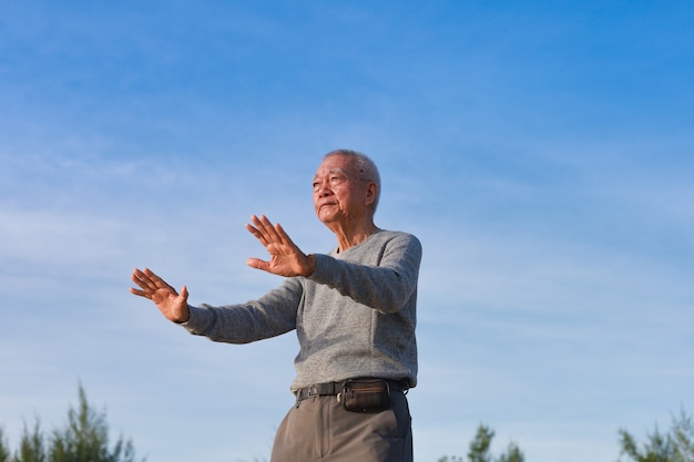 Photo asian senior old man practice taichi chinese kungfu on the beach