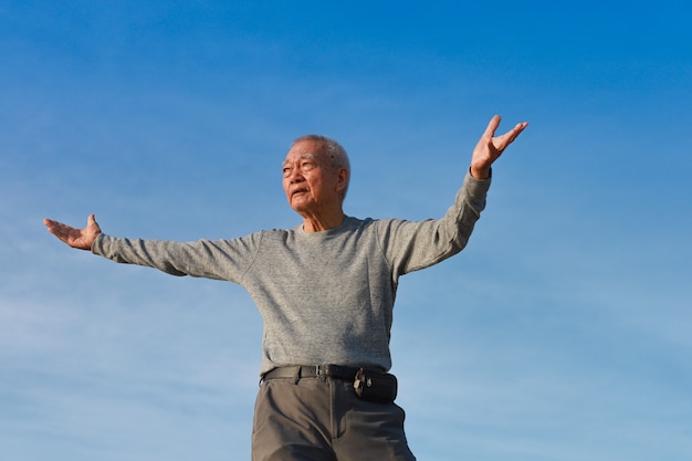 L'uomo anziano maggiore asiatico pratica il kungfu cinese di taichi sulla spiaggia