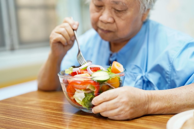 アジアのシニア患者が病院で朝食を食べる