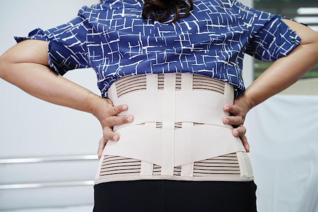 Asian senior wearing elastic support belt can help reduce back pain