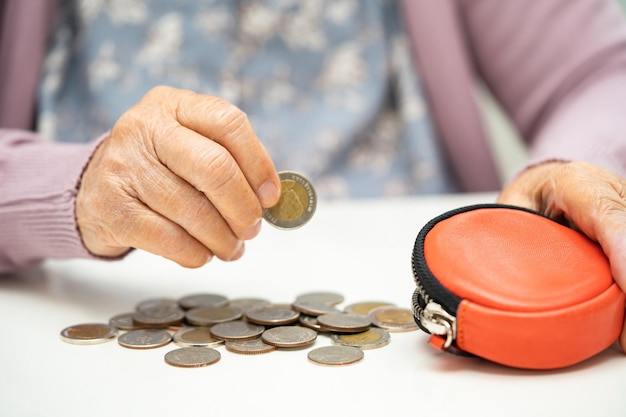 Asian senior woman holding counting coin money in purse Poverty saving problem in retirement