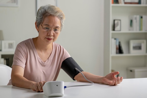 Asian senior woman measuring blood pressure at home