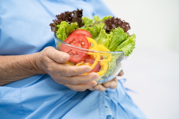 Paziente asiatico senior della donna che mangia cibo sano di verdure per la colazione