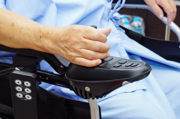 Paziente asiatico senior della donna sulla sedia a rotelle elettrica.