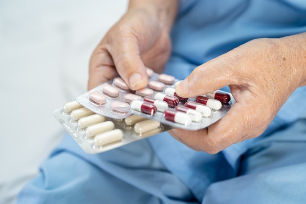 Photo asian senior woman patient holding capsule pills in hospital