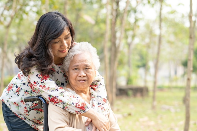 Asian senior woman patient with care on wheelchair in park