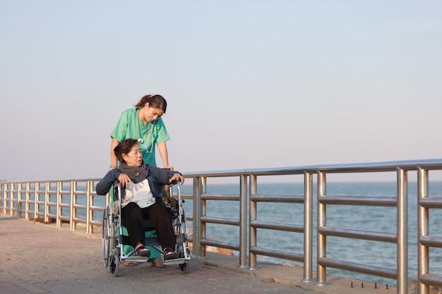 공원 병원에서 의사 유니폼 여자와 휠체어에 앉아 아시아 수석 여자