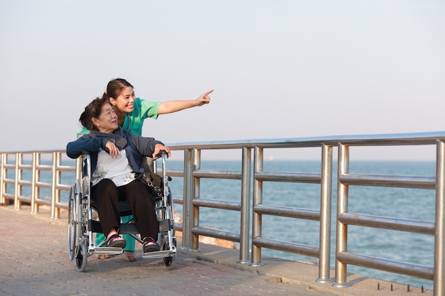 Asian senior woman sitting on the wheelchair  with woman in doctor uniform in the park hospital