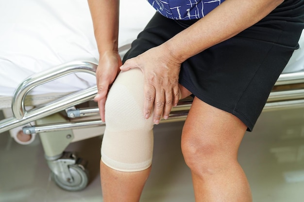 Asian senior woman wearing elastic support knee brace for reduce pain