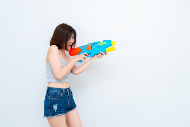 Азиатская сексуальная женщина с водой из пистолета в руке на белом фоне