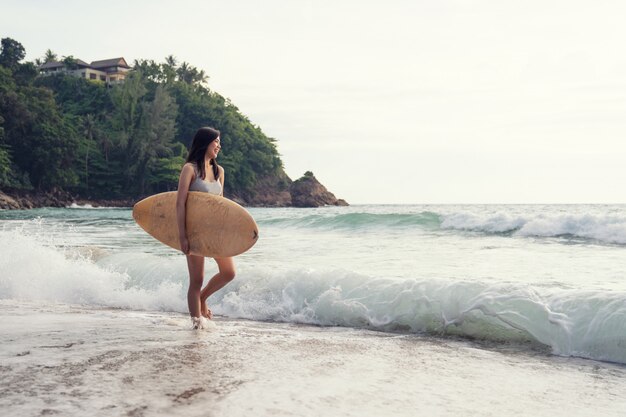 A asian sexy young woman walking on beach with surfboard at Phuket Thailand